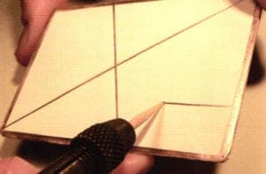 Once the layer is dry, we transfer the design by scratching it with the tip of a scribing tool.